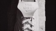 Close-up of white Nike Atelier sneaker tongue with embossed logo and laces.