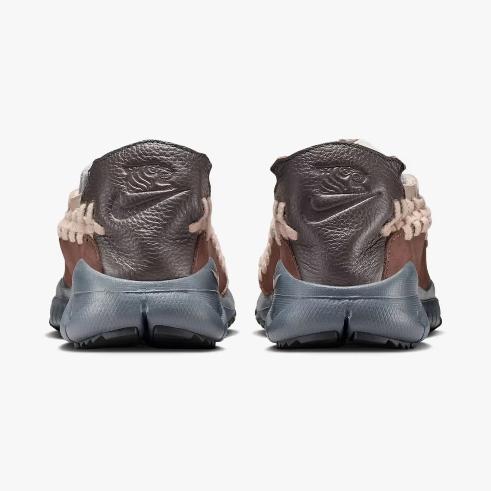 Pair of sneakers with dark brown leather heel tabs embossed with a tiger and Nike swoosh logo, beige woven accents, and blue soles.