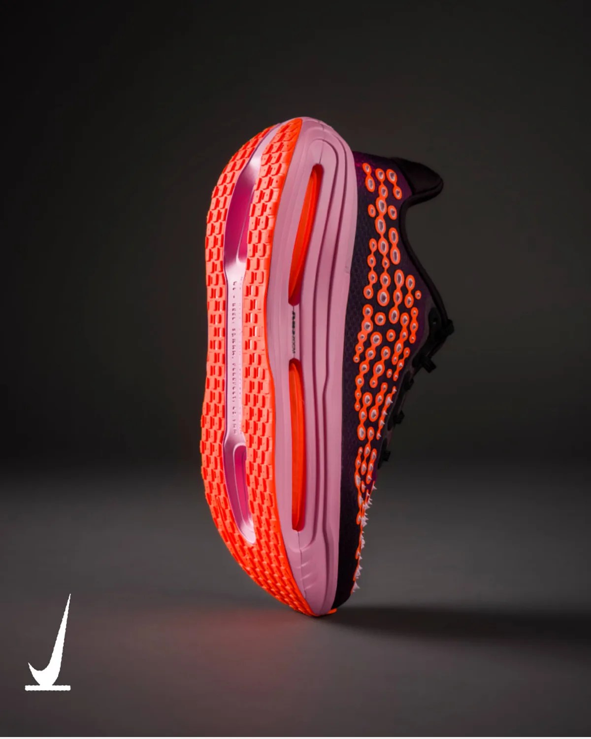 Black and orange Nike running shoe with a thick pink and orange sole, shown from the side on a dark background.