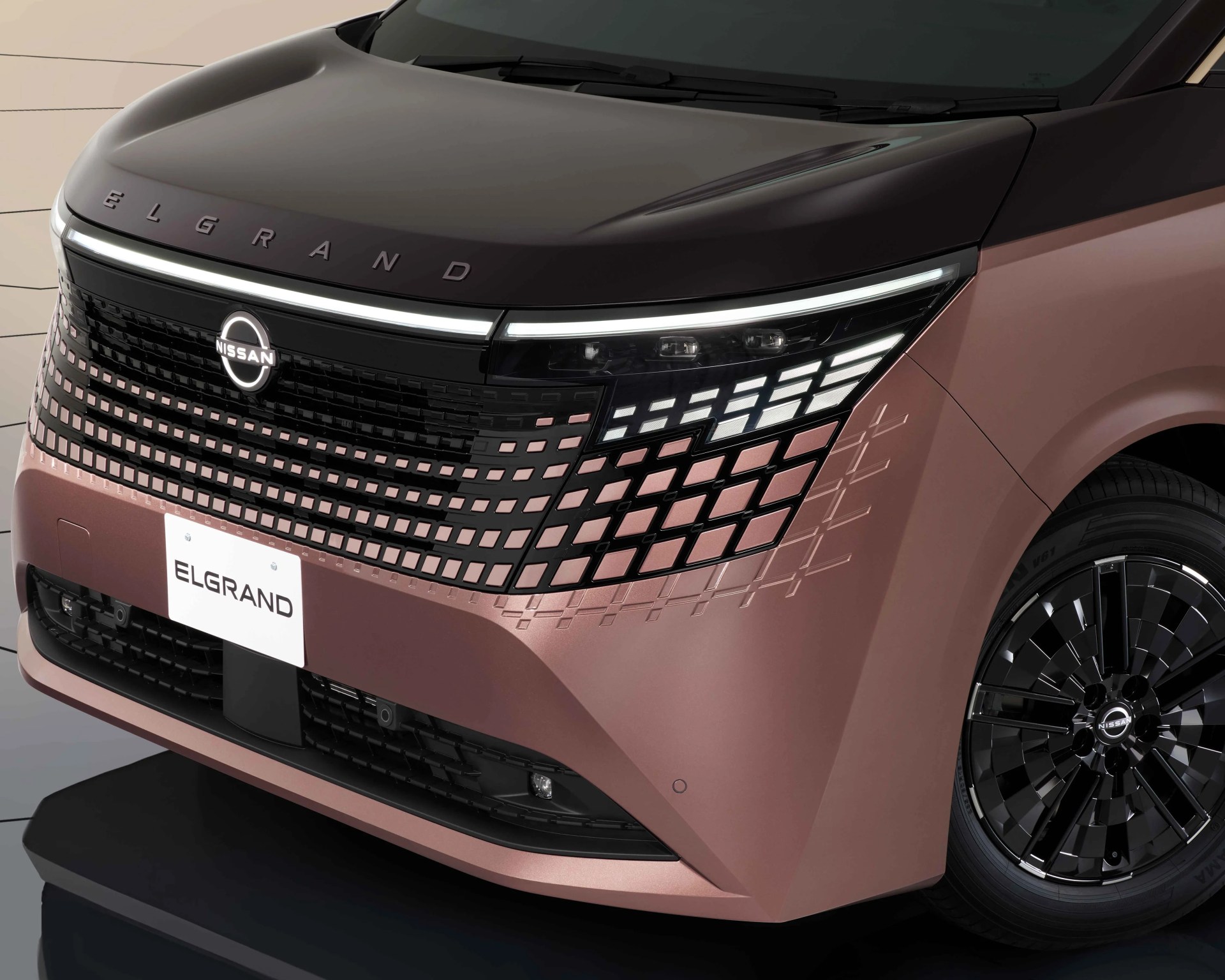Front view of a pink Nissan Elgrand with illuminated grille and black hood.