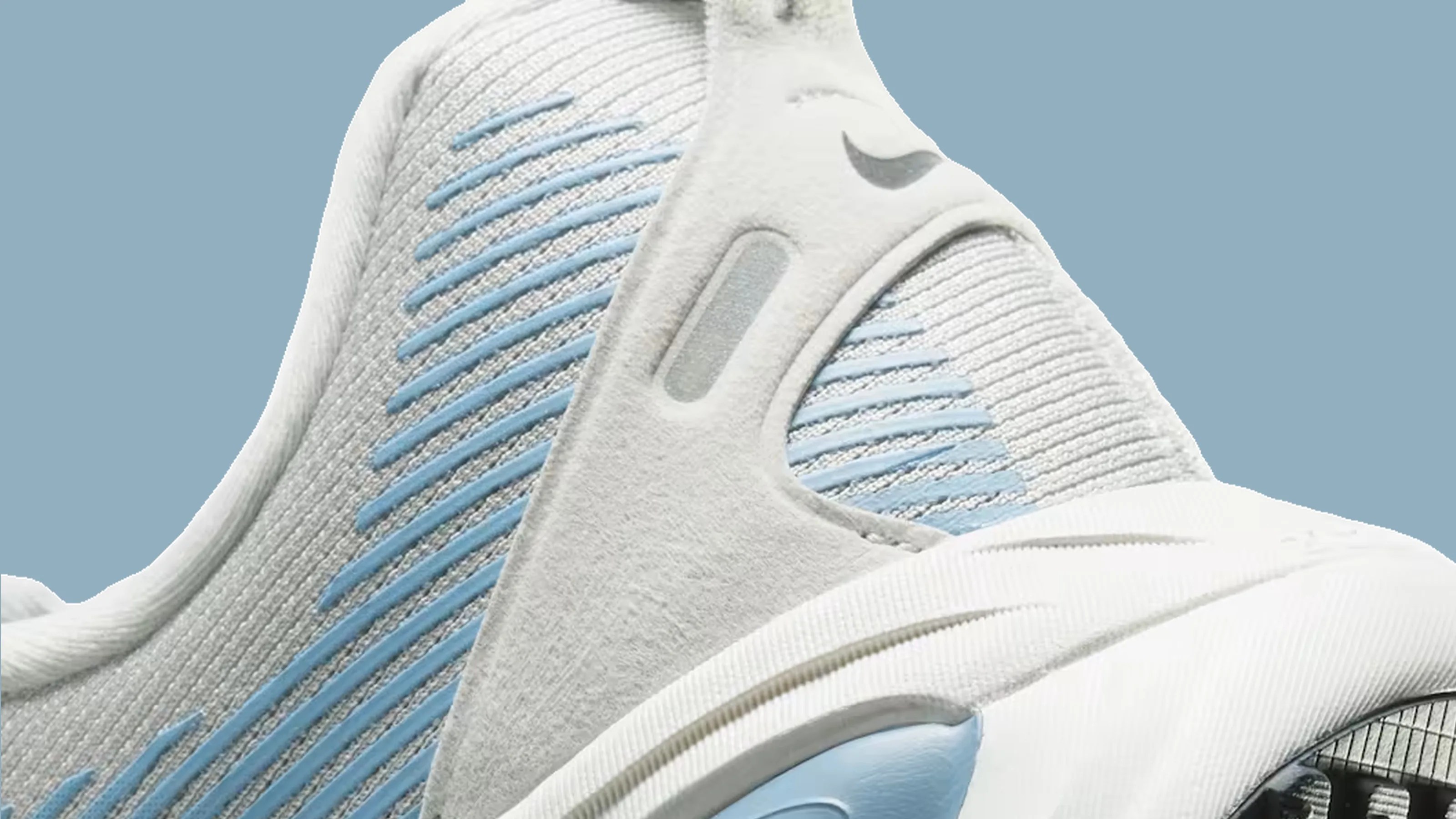 Close-up of a white and light blue Nike sneaker with knit fabric and a visible air cushion in the sole.