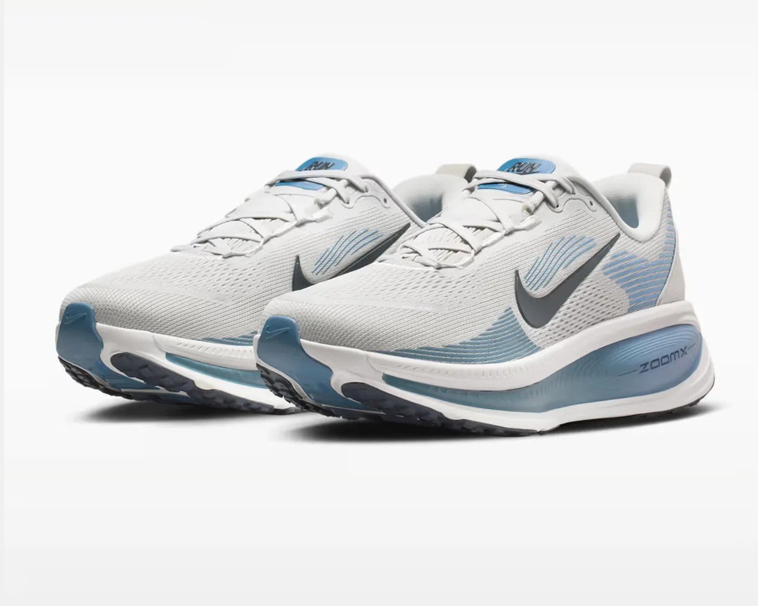 Pair of white and light blue Nike ZoomX running shoes with black swoosh logos.