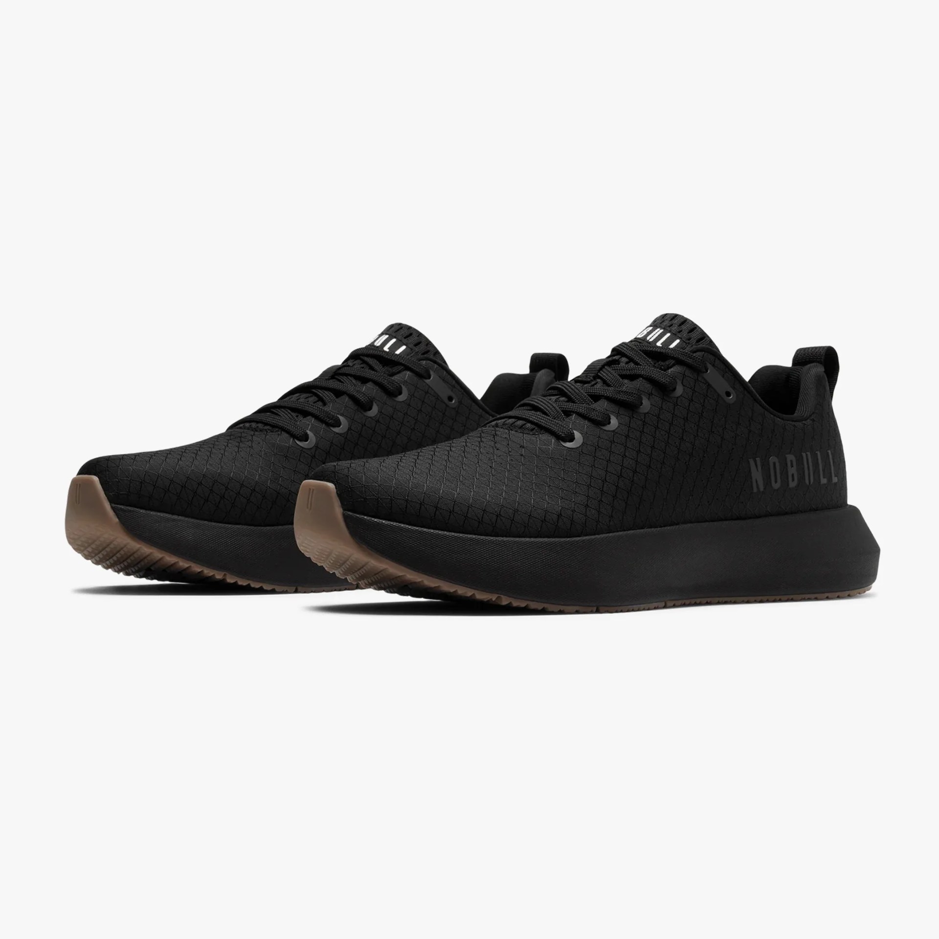 Pair of black NOBULL sneakers with textured upper and brown rubber soles on a white background.