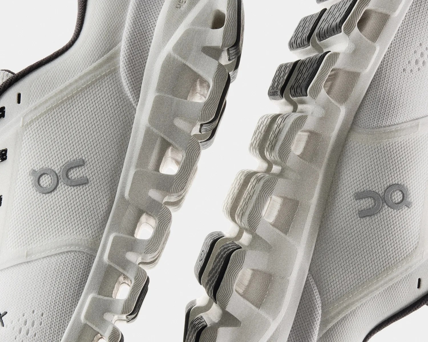 Close-up of white athletic shoes with textured mesh fabric and segmented soles featuring black traction pads.