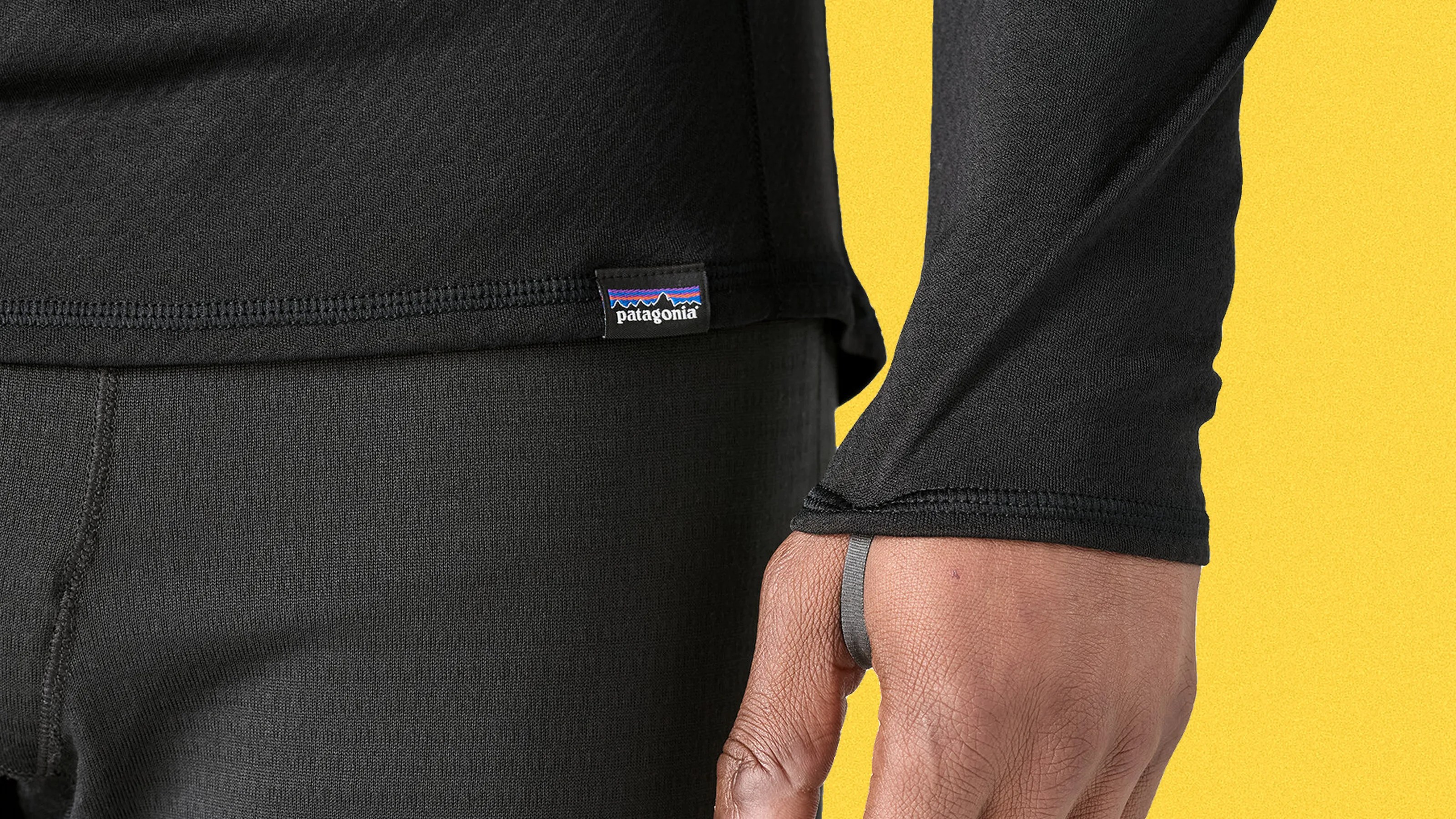 Close-up of a person wearing black Patagonia long-sleeve top and black pants with a yellow background.