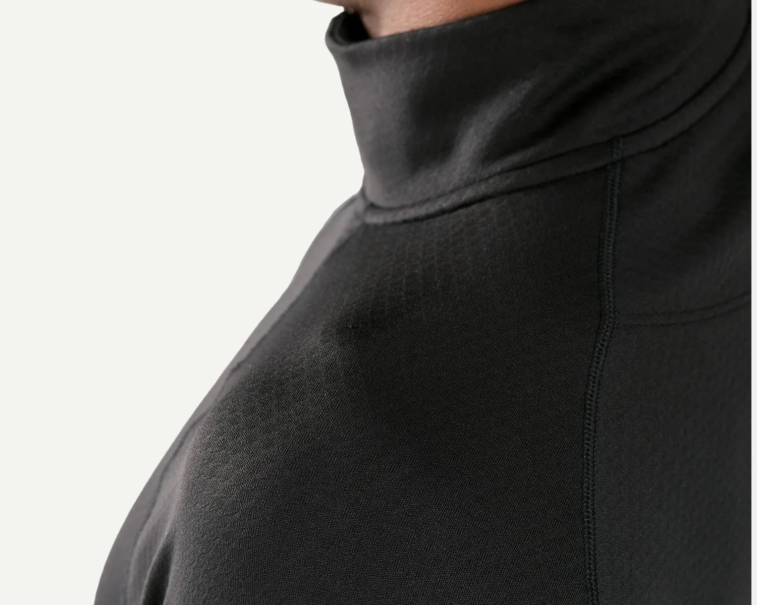 Close-up of a black high-neck garment with visible stitching and textured fabric.