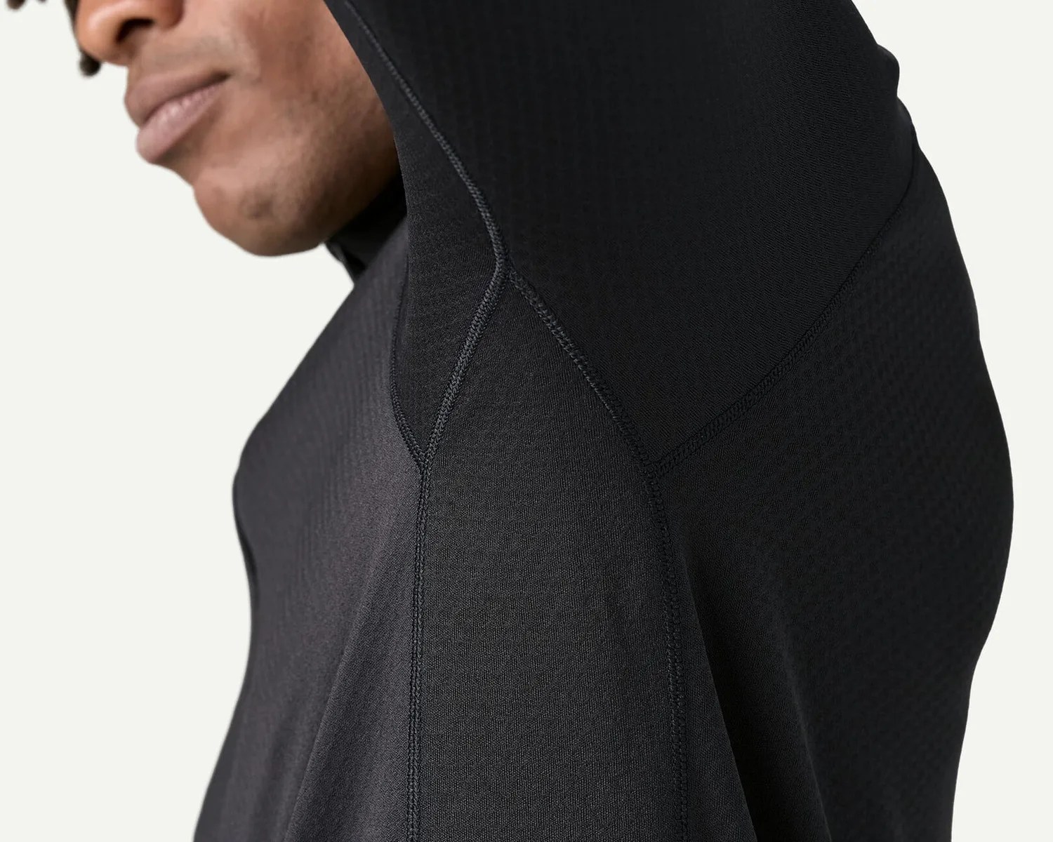 Close-up of a person wearing a black textured hooded garment with visible seam details.