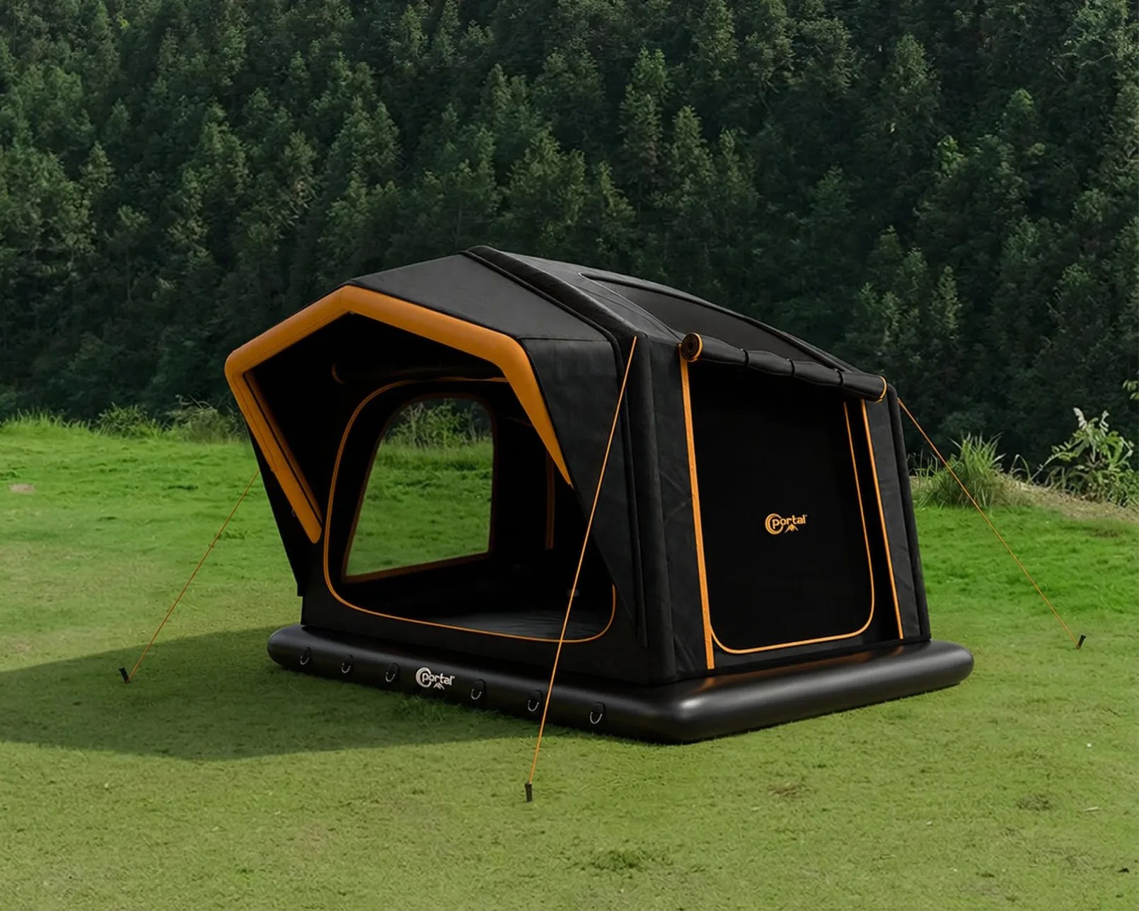 Black and orange inflatable camping tent set up on green grass with forest background.