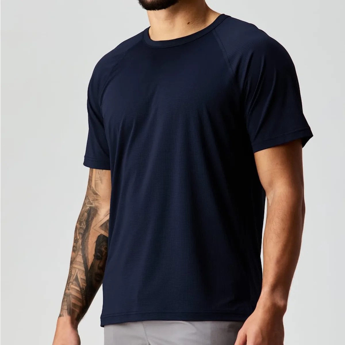 Navy blue short-sleeve athletic T-shirt worn by a person with a tattooed arm.