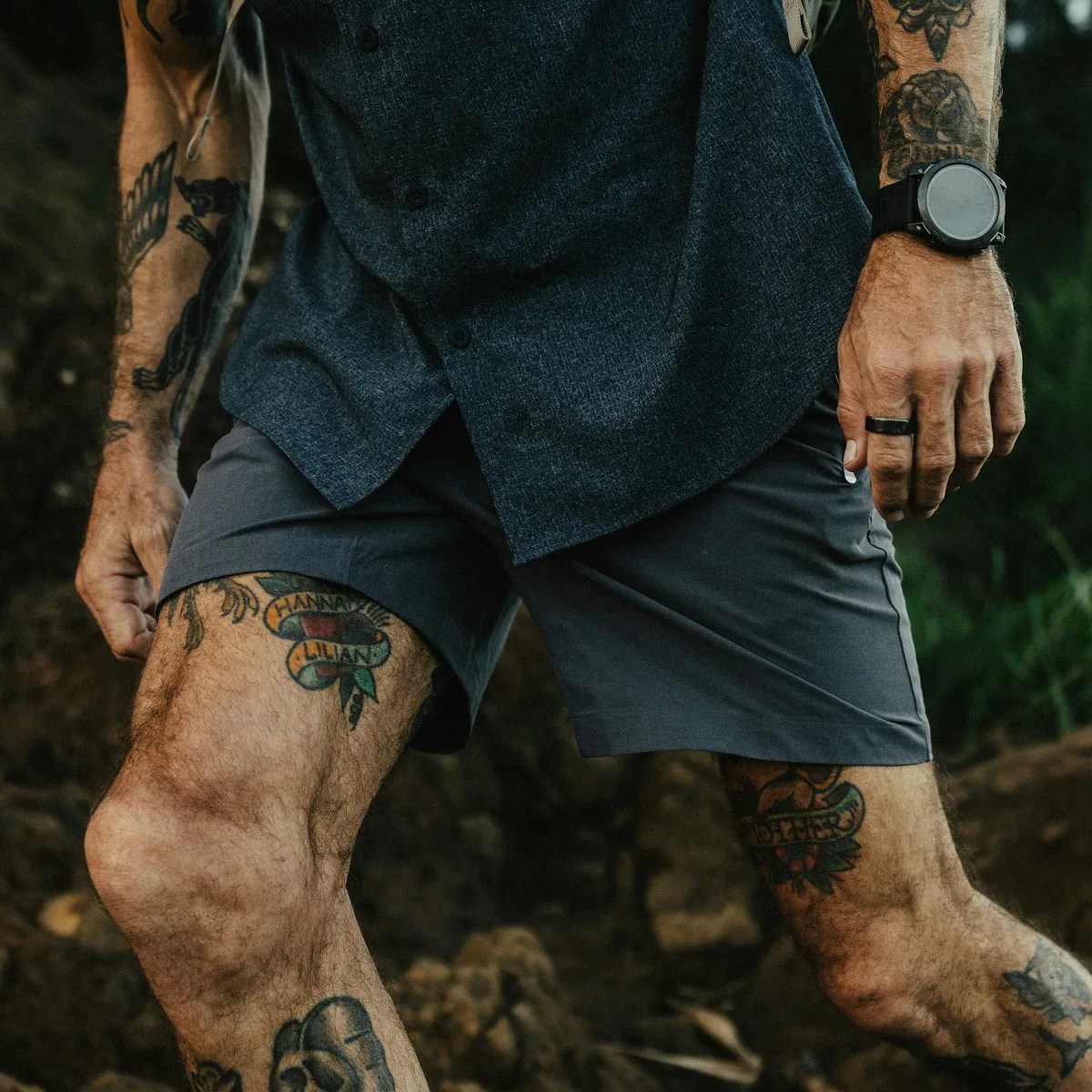 Gray athletic shorts worn by a tattooed person with a black watch and ring.