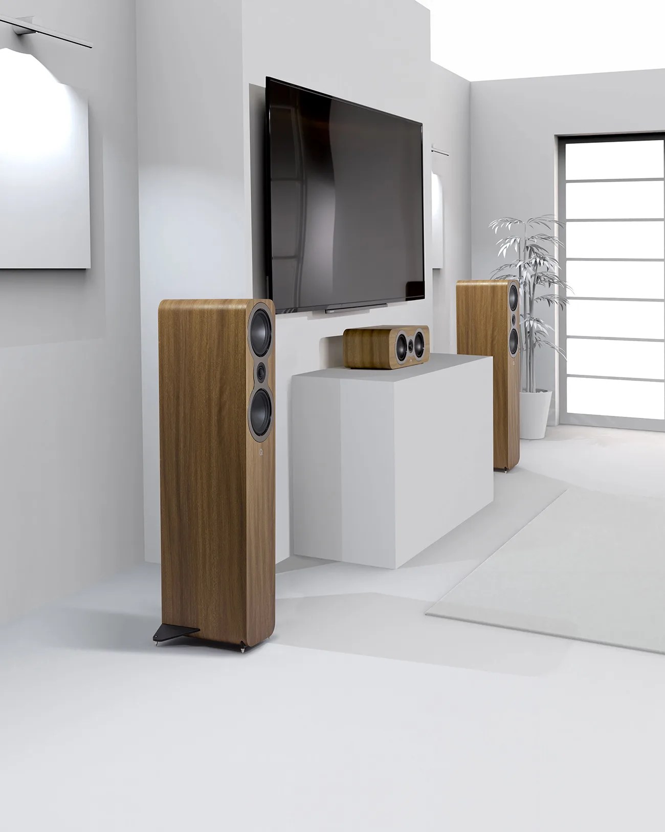 Pair of tall wooden floor-standing speakers and a matching center speaker below a wall-mounted flat-screen TV in a modern white living room.