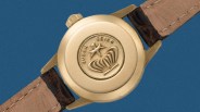 Gold watch case back with embossed "Queen Seiko" logo and brown leather strap.