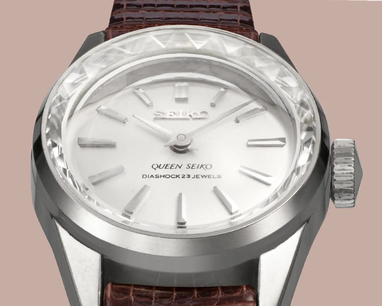 Silver Seiko wristwatch with a white dial, faceted crystal, and brown leather strap.