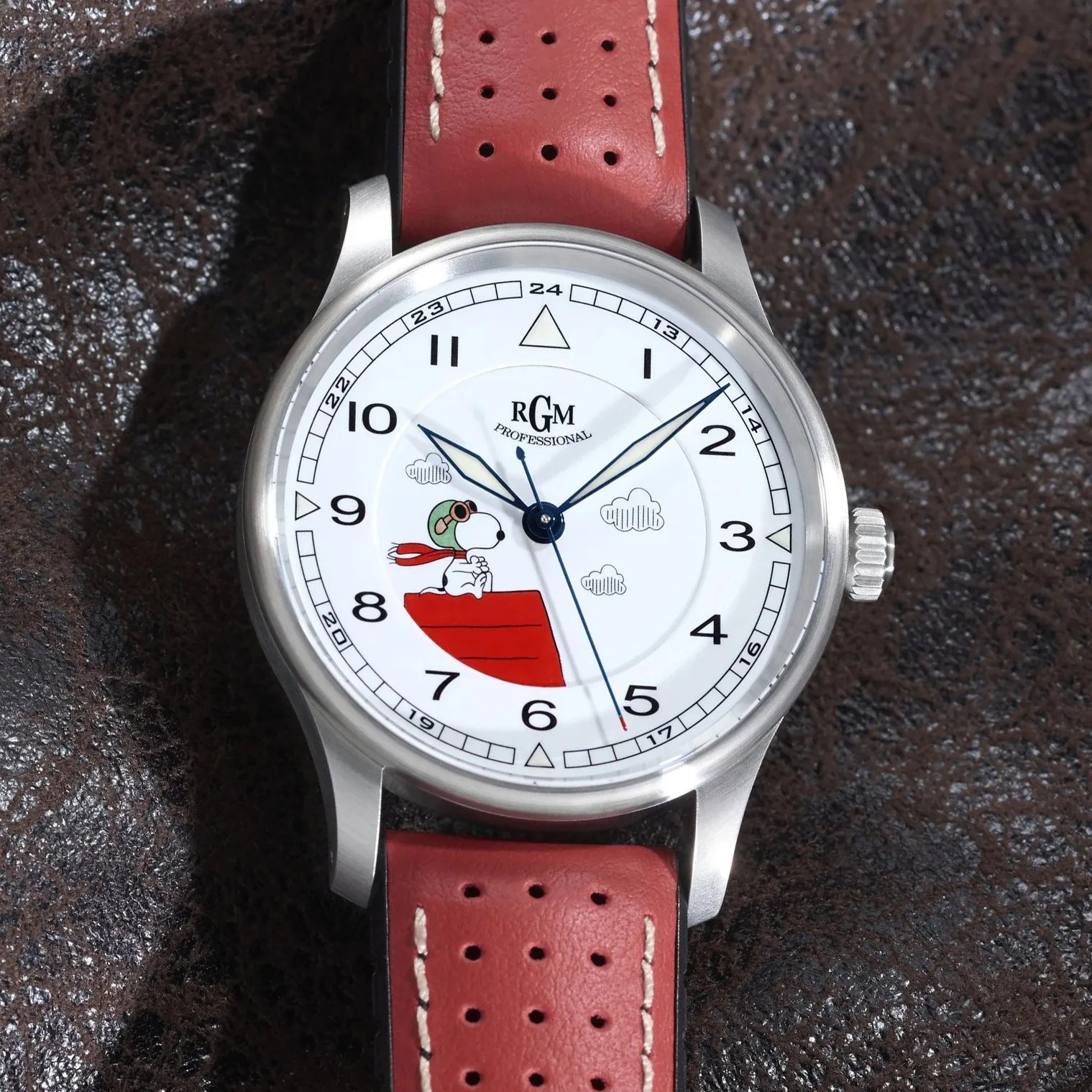 Round silver wristwatch with white dial featuring Snoopy on a red doghouse and a red perforated leather strap.
