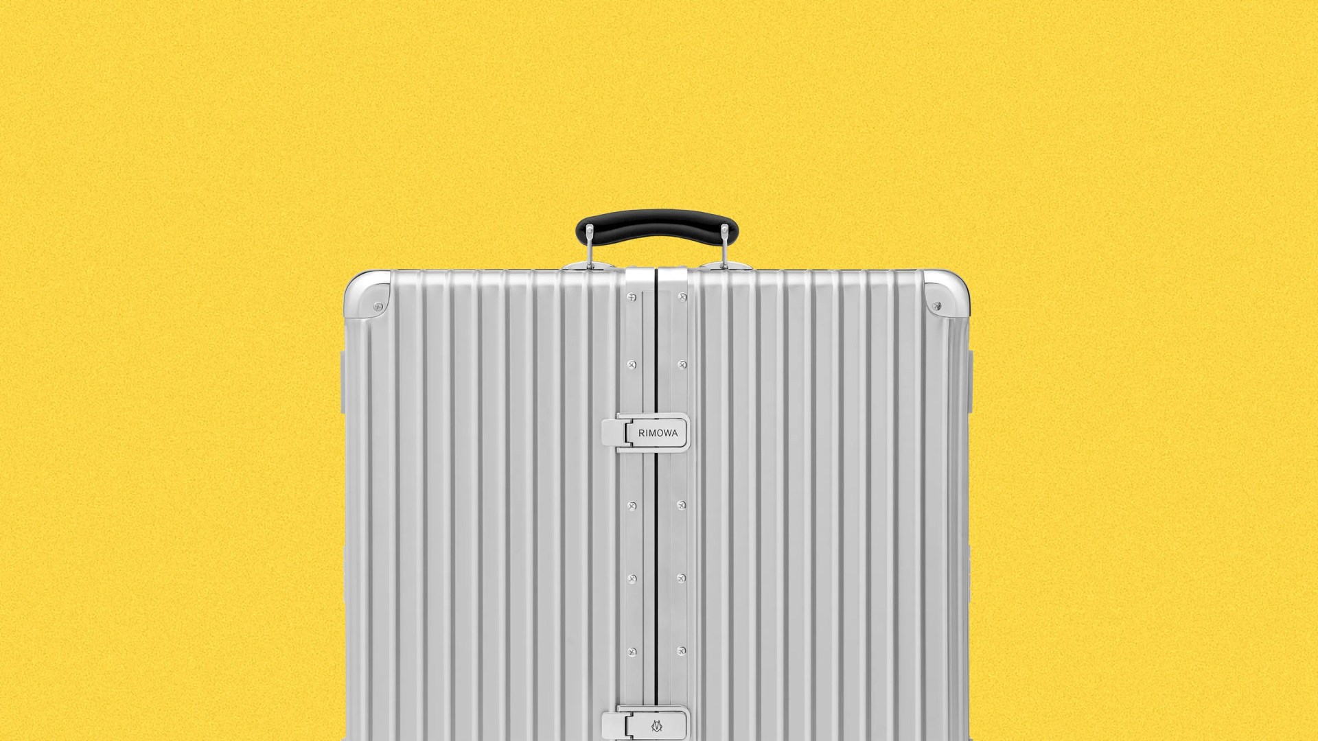 Silver hard-shell Rimowa suitcase with vertical grooves and black handle against yellow background.