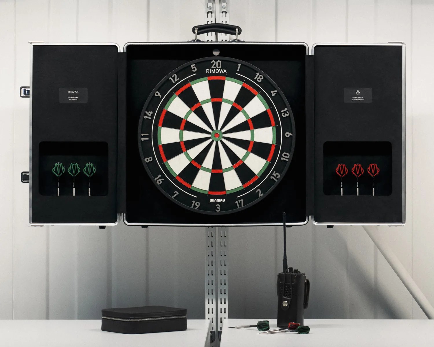 Dartboard set with black, white, red, and green segments inside an open black case with green and red darts on each side.