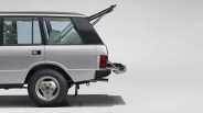 Silver SUV with rear hatch and tailgate open, showing beige interior seats and spare tire inside.