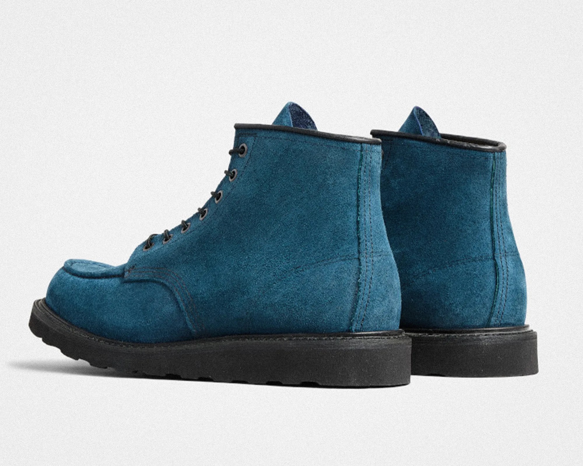 Pair of blue suede lace-up boots with black soles on a white background.