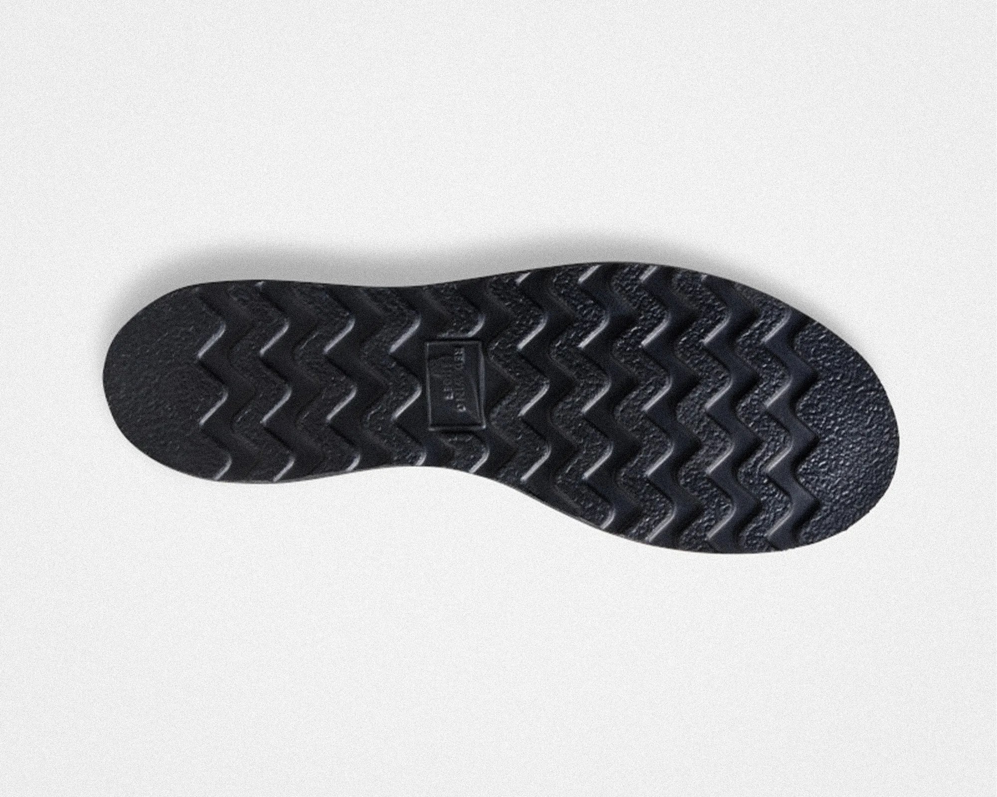 Black rubber shoe sole with zigzag tread pattern on a white background.
