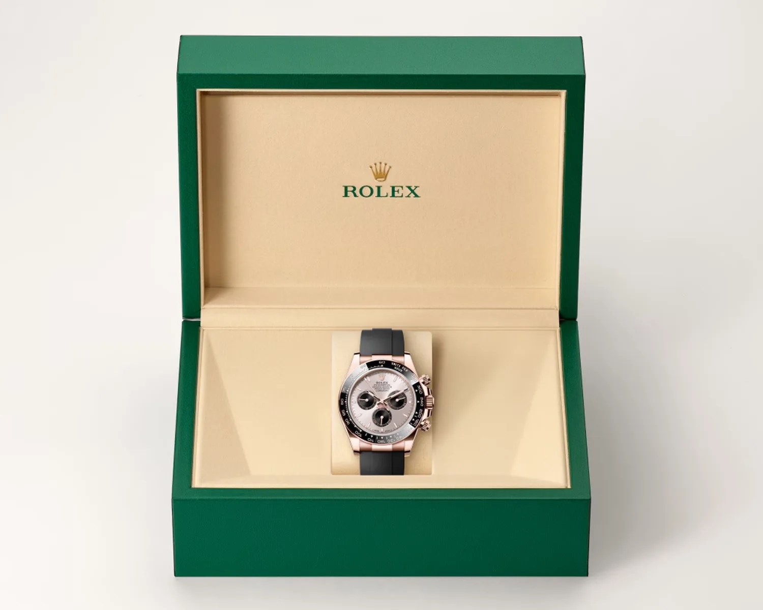 Rolex watch with black rubber strap and silver dial in an open green and beige Rolex box.