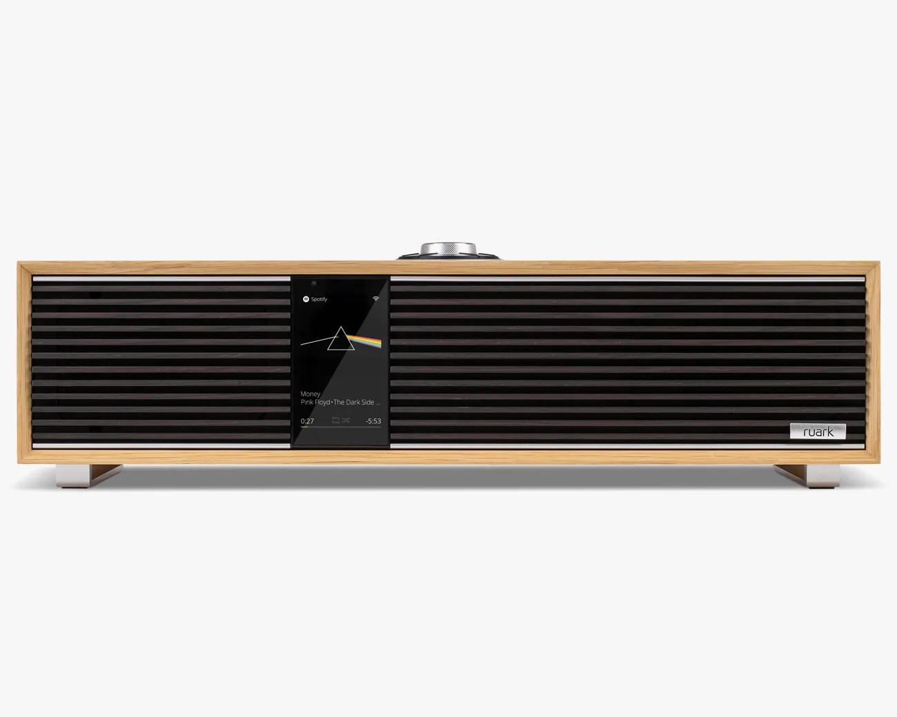 Rectangular wooden-framed speaker with black horizontal grille and central digital display showing Pink Floyd song.