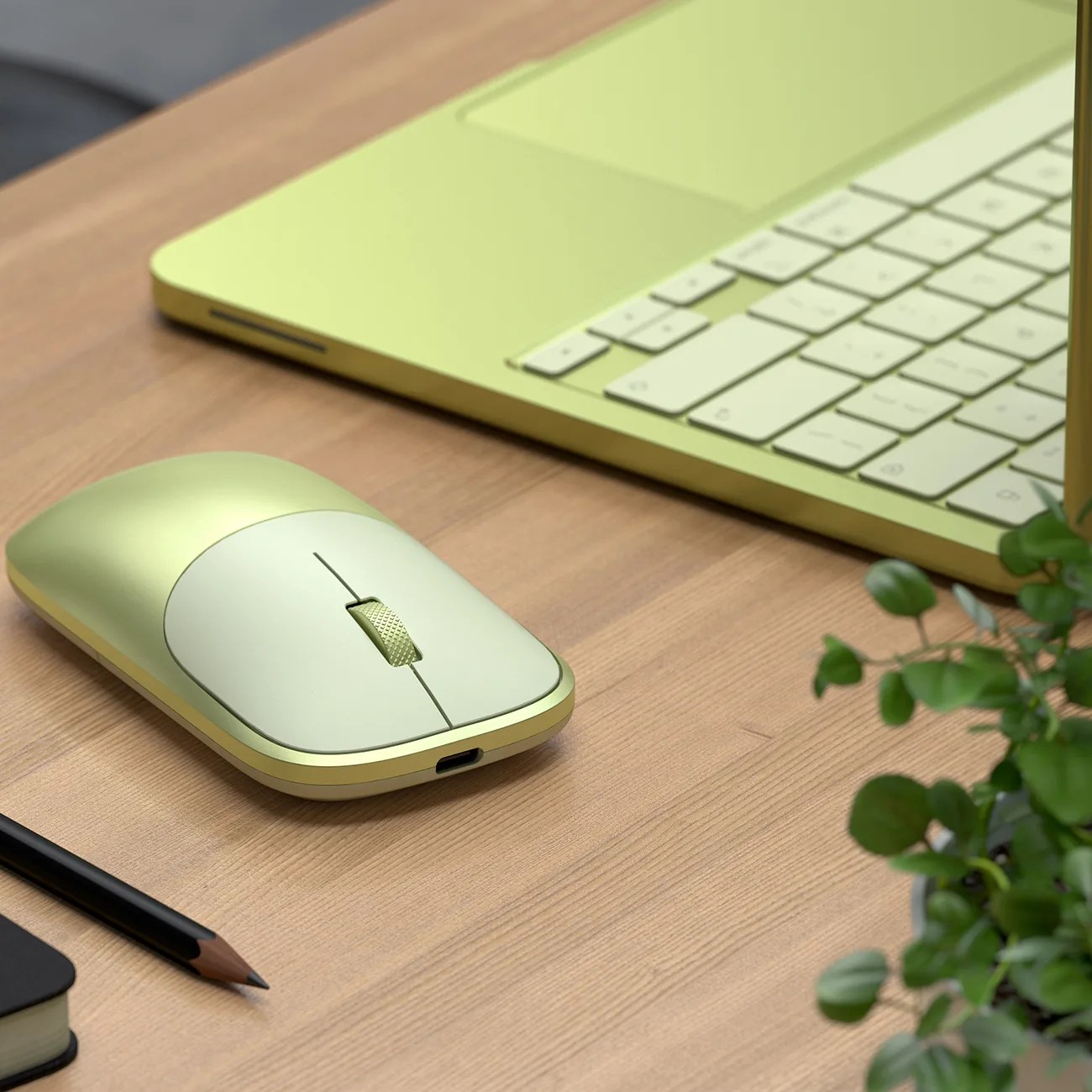 Sleek green wireless mouse with scroll wheel next to a matching green laptop on a wooden desk.
