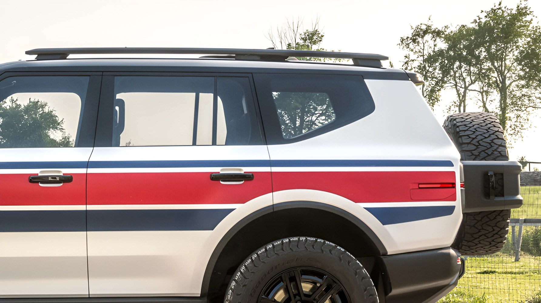 White SUV with red and blue racing stripes, black roof rails, and a rear-mounted spare tire.