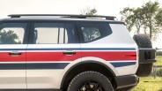 White SUV with red and blue racing stripes, black roof rails, and a rear-mounted spare tire.