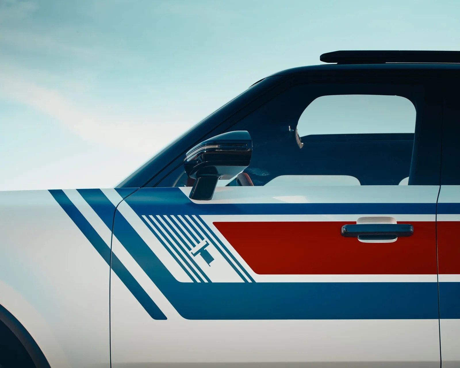 Side view of a white vehicle door with blue and red geometric stripes and a black side mirror.