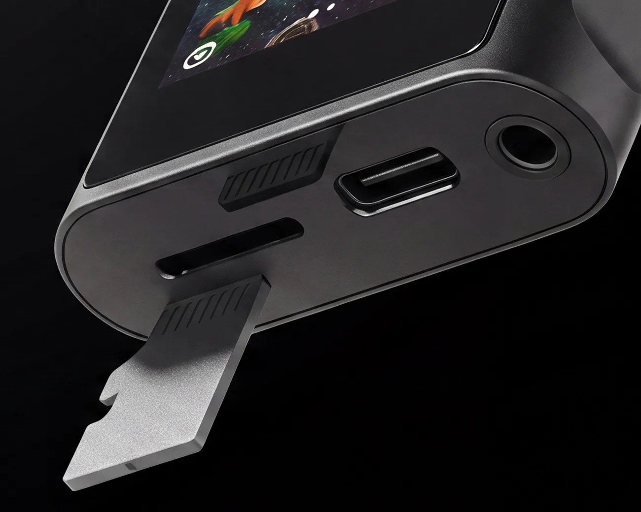 Close-up of a black electronic device showing a metal kickstand, USB-C port, headphone jack, and a slot on a black background.