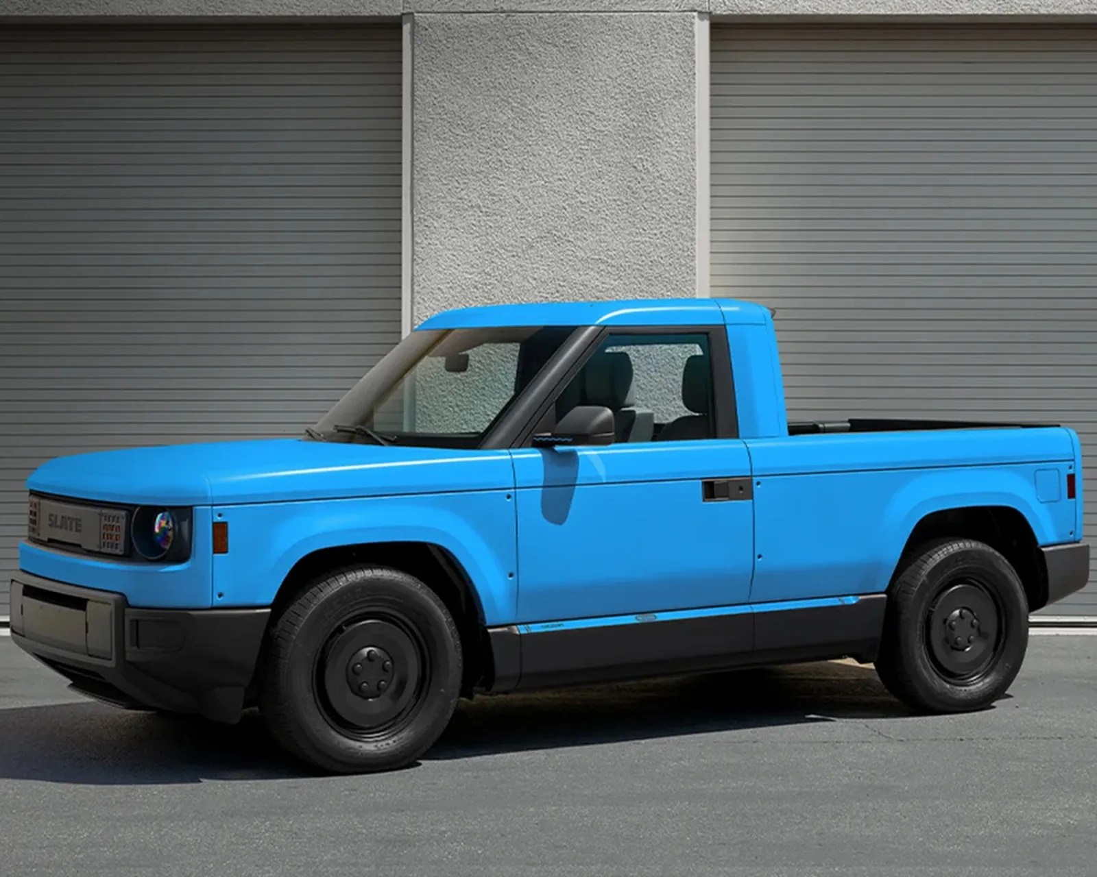 Bright blue compact pickup truck with black wheels parked in front of gray garage doors.
