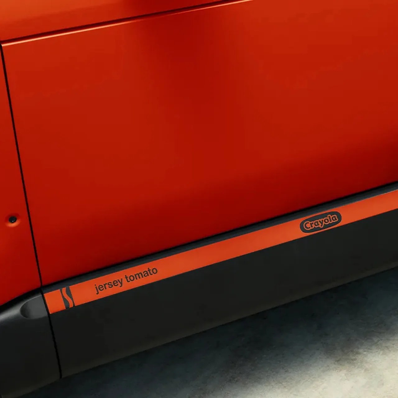 Close-up of a red-orange car door with a black side skirt featuring the text "jersey tomato" and the Crayola logo.