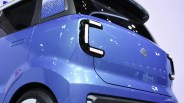 Rear corner of a blue Suzuki car with distinctive C-shaped taillights and black roof spoiler.
