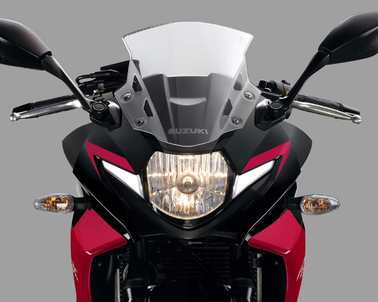 Front view of a black and red Suzuki motorcycle with clear windshield, central headlight, and side mirrors.