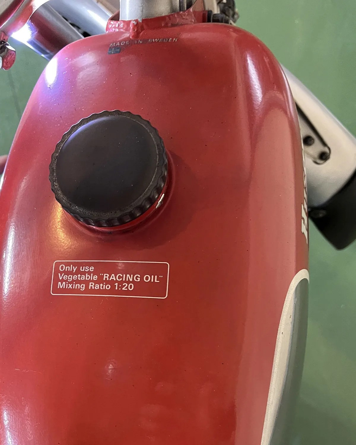 Red fuel tank with black cap and white label reading "Only use Vegetable 'RACING OIL' Mixing Ratio 1:20
