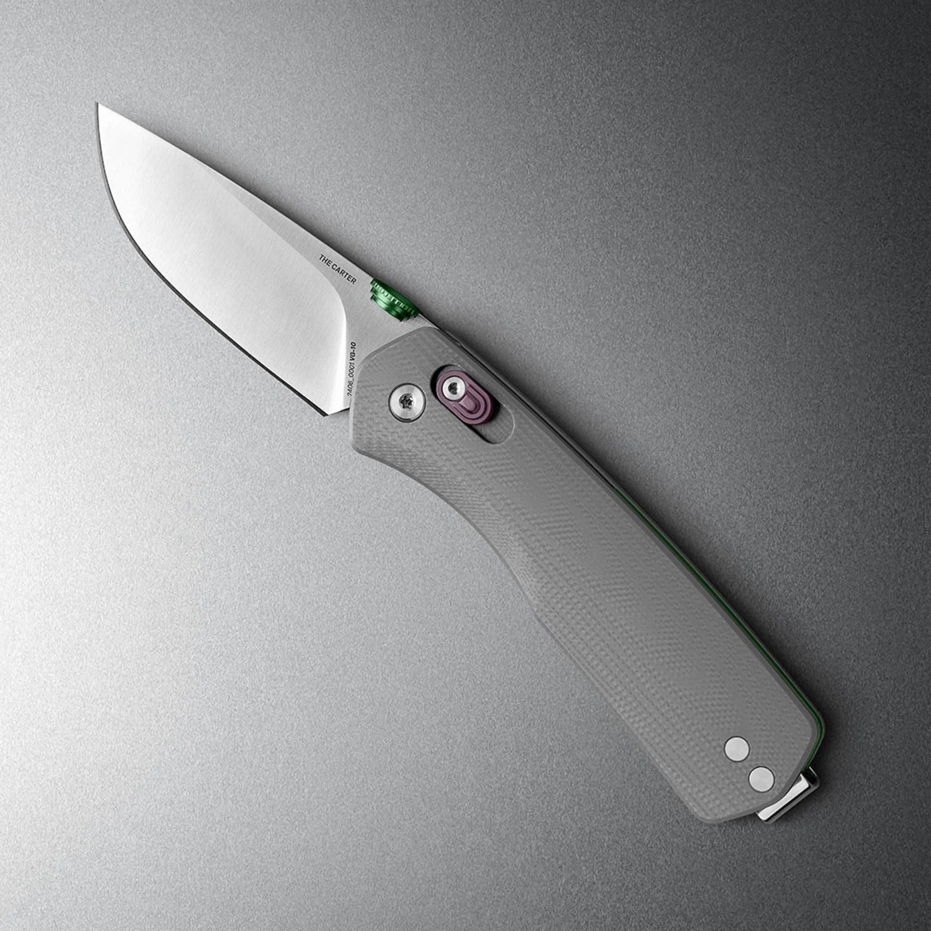 Folding knife with a silver blade labeled "THE CARTER" and a gray textured handle with purple and green accents.