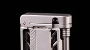 Close-up of a silver metal multi-tool with a hinge and grooved cylindrical component on a black background.