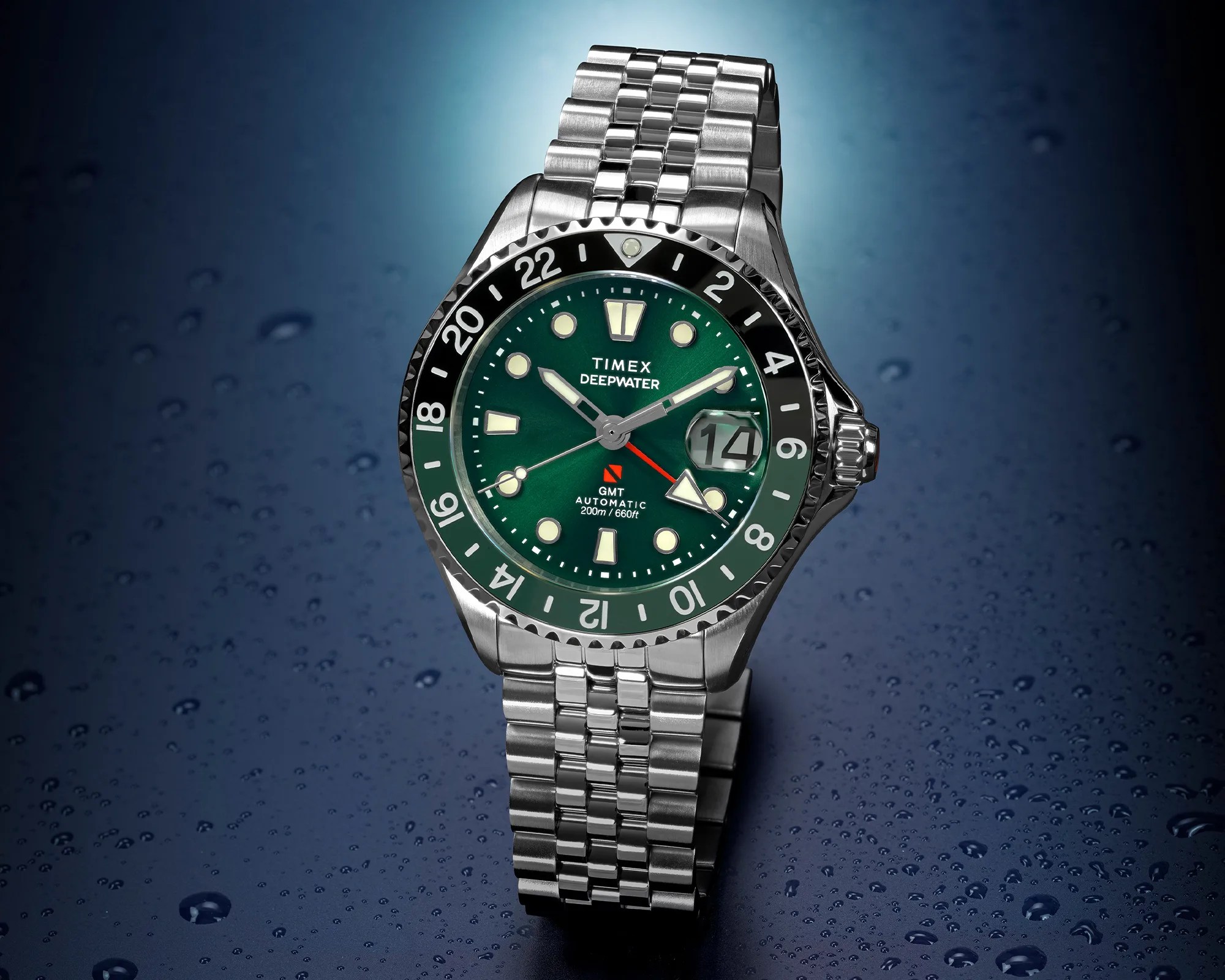 Stainless steel Timex Deepwater GMT watch with green dial and black bezel on a wet dark surface.