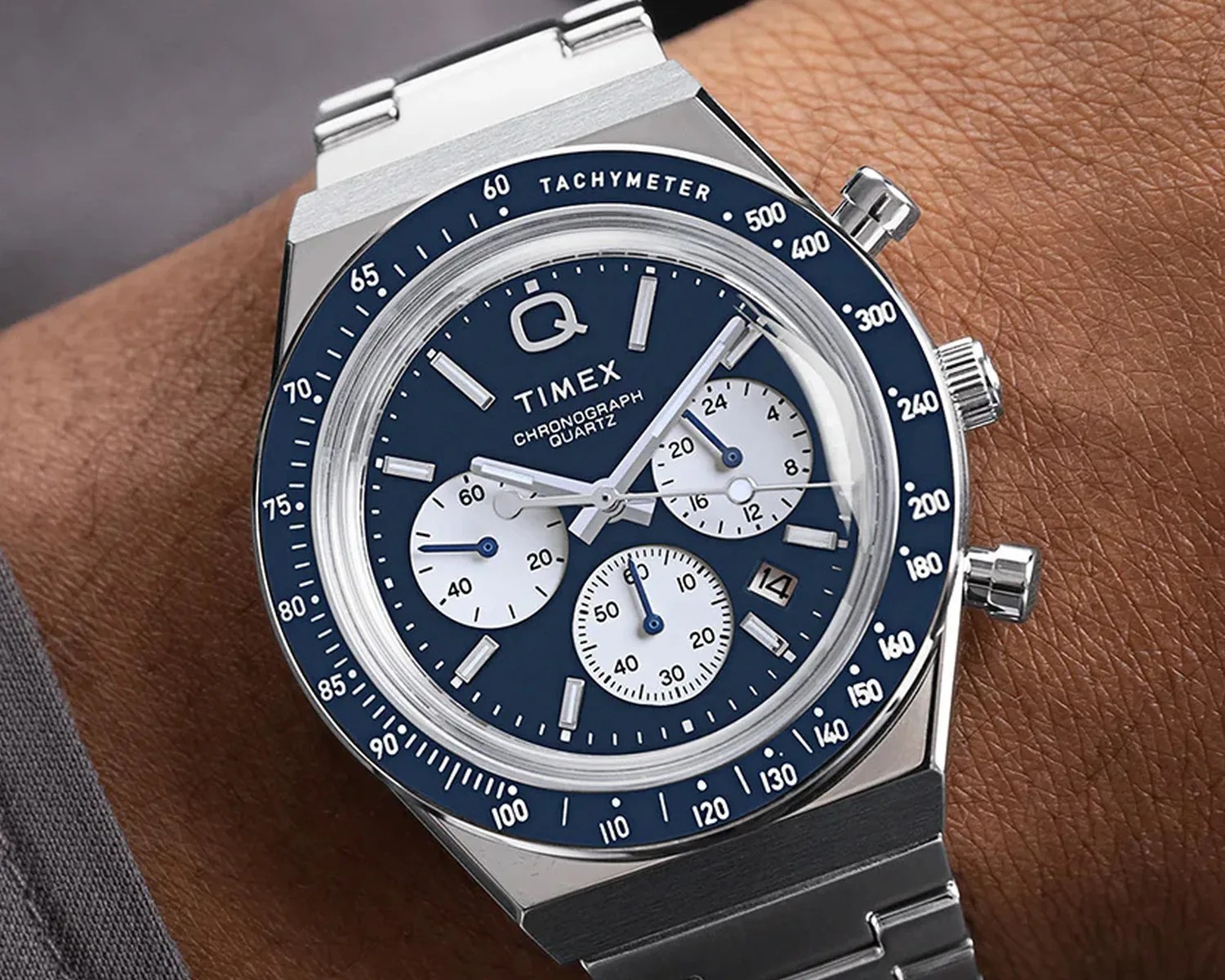 Silver Timex chronograph watch with blue dial, white subdials, tachymeter bezel, and metal bracelet on wrist.