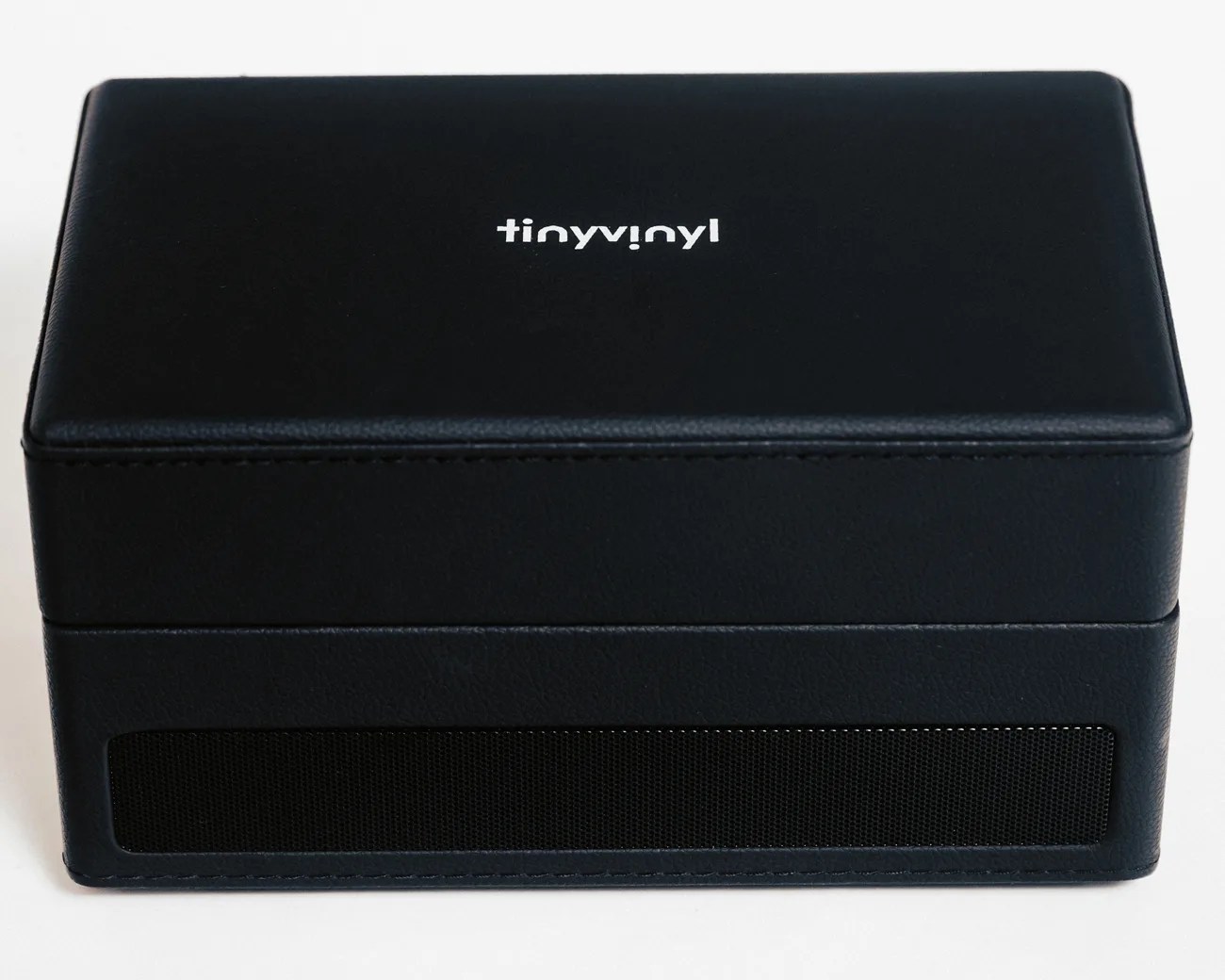 Black rectangular leather case with "tinyvinyl" logo on top and a mesh panel on the front side.