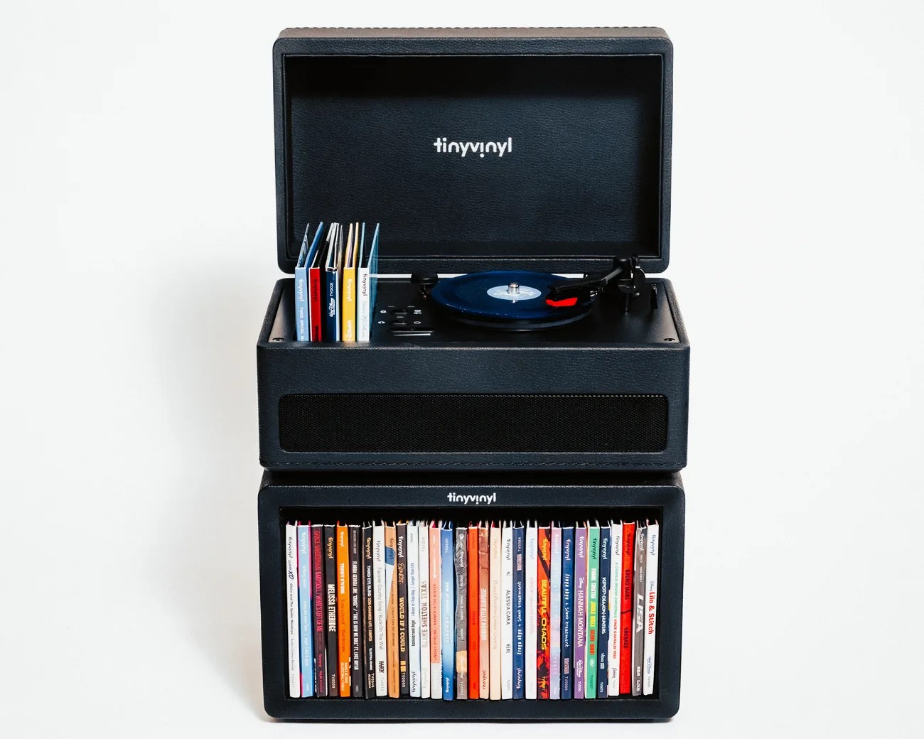 Black Tiny Vinyl record player with a stack of colorful vinyl record sleeves in a matching black storage box.