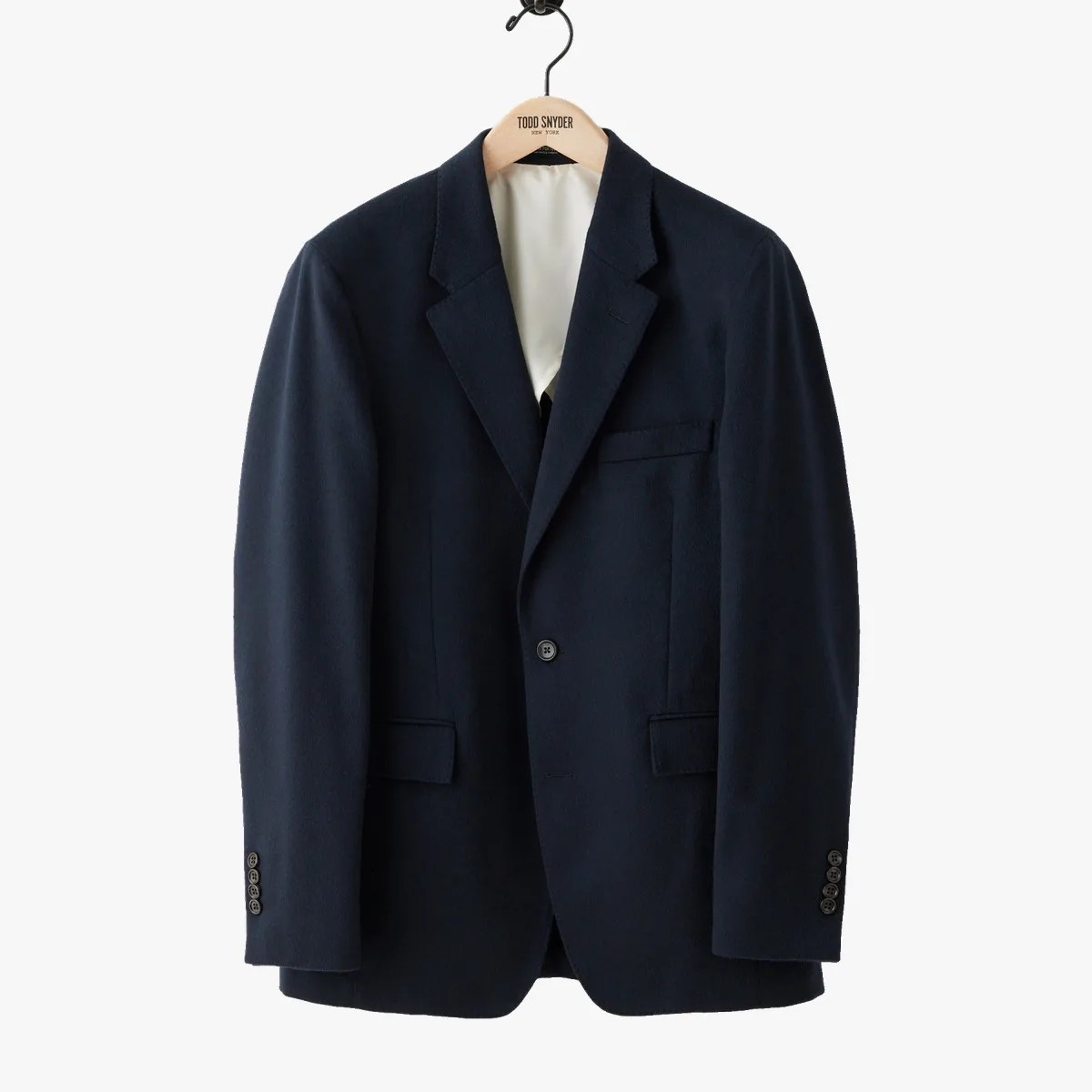 Navy blue single-button blazer with notch lapels and flap pockets on a wooden hanger.