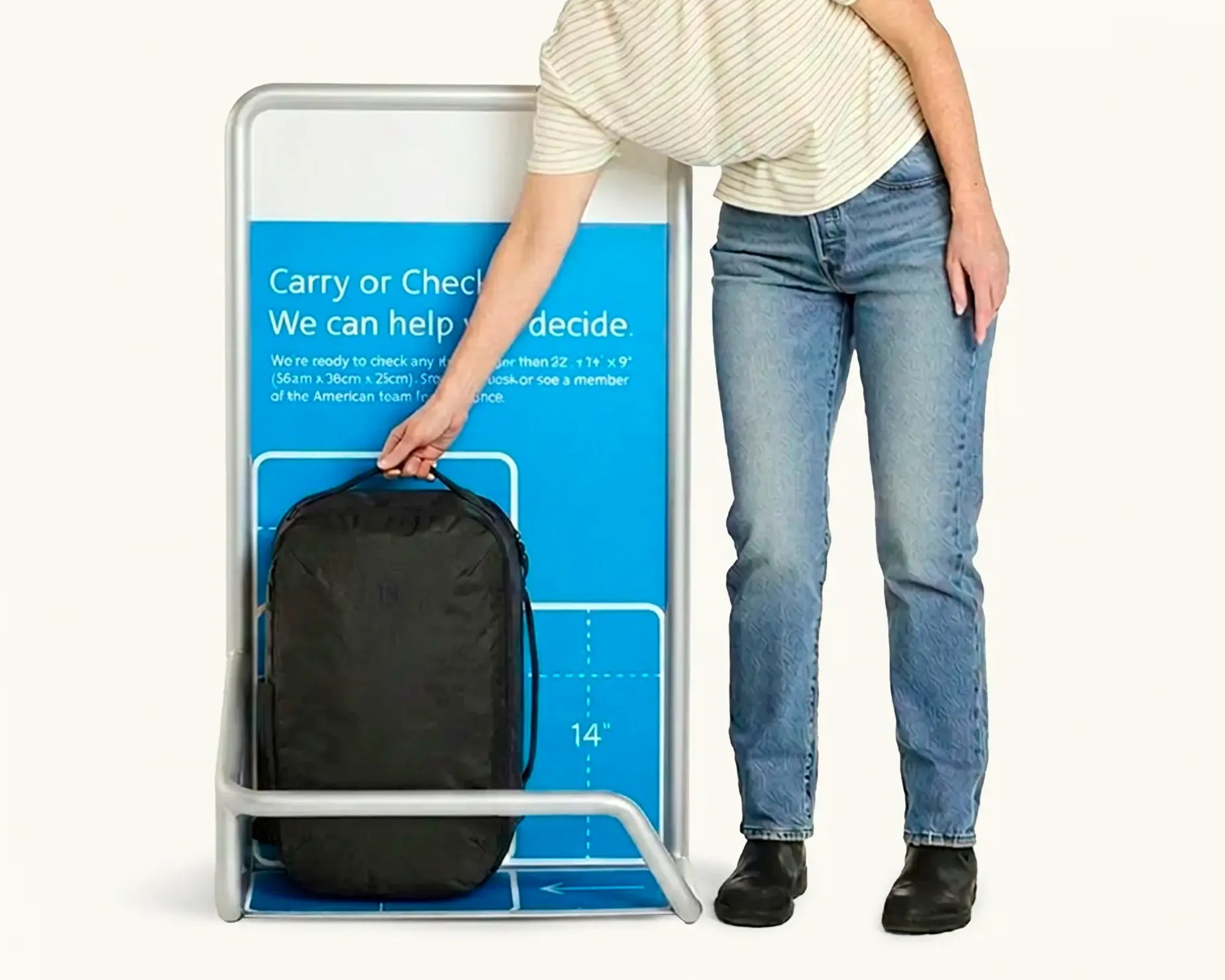 Person in striped shirt and jeans placing a black backpack into a blue and white luggage size checker.