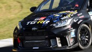 Front view of a black Toyota GR racing car with sponsor decals and blue and yellow graphics on the hood.