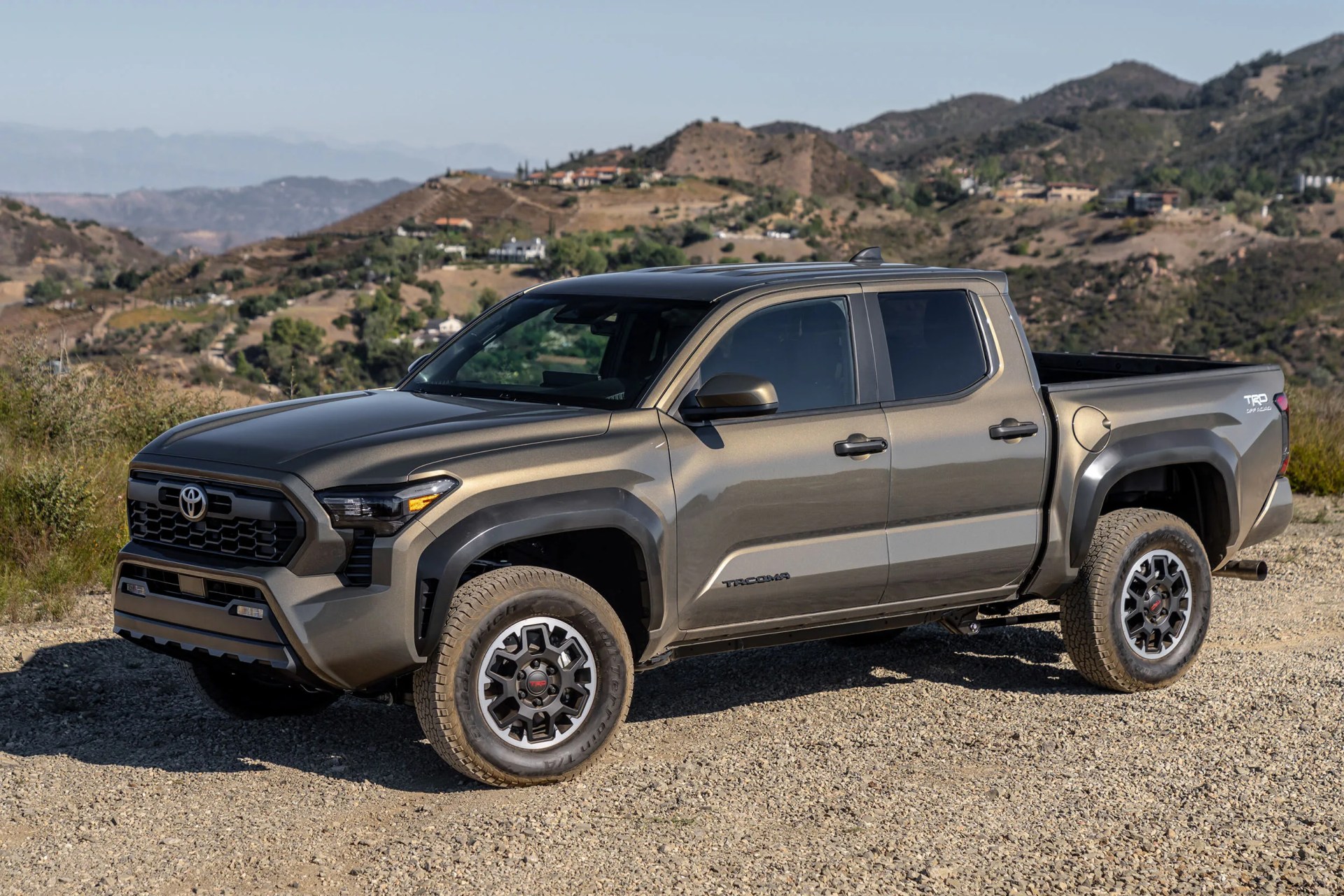 Gray Toyota Tacoma TRD pickup truck parked on a gravel road with hills in the background.