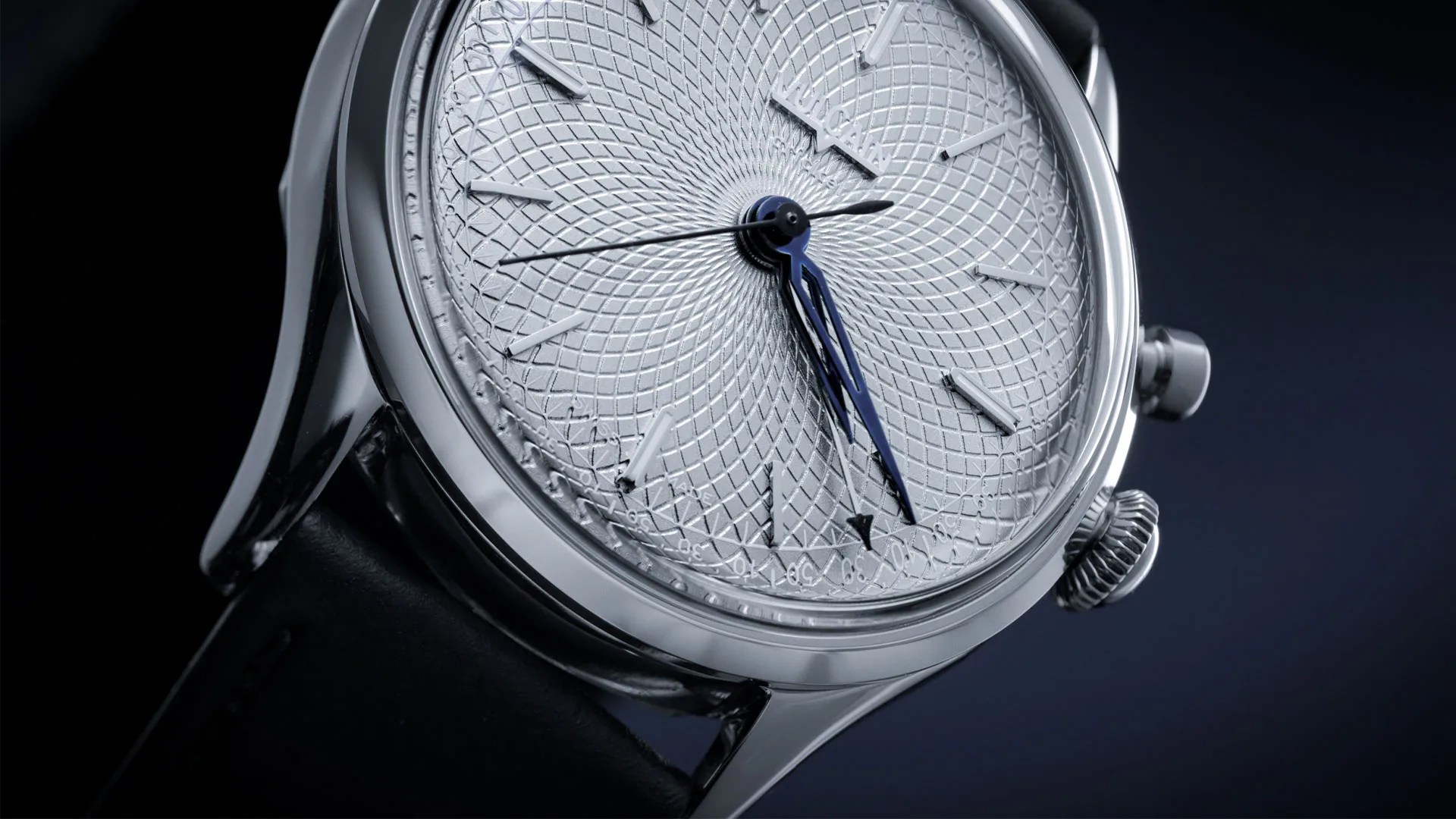 Close-up of a silver wristwatch with a textured dial, blue hour and minute hands, and a black leather strap.