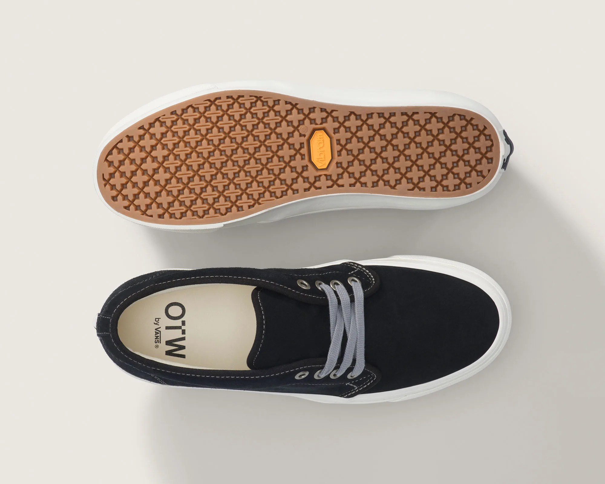 Black canvas sneaker with gray laces and white rubber sole showing patterned brown outsole.