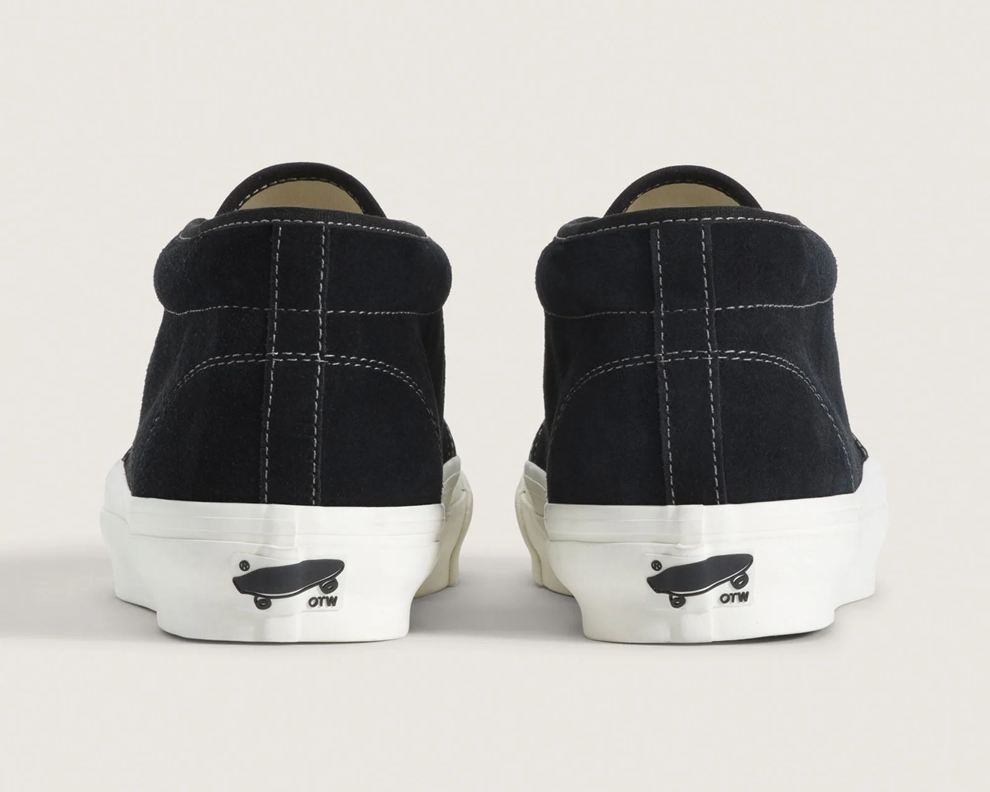 Pair of black suede sneakers with white rubber soles and skateboard logo on the heel.