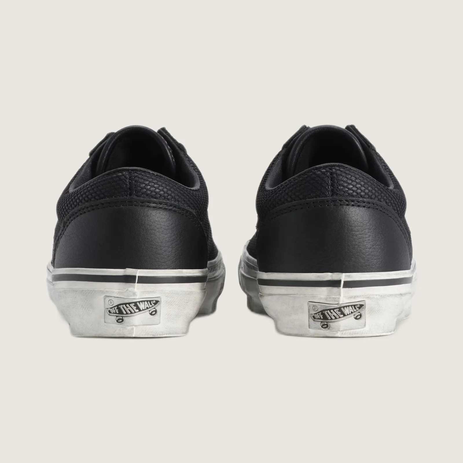 Pair of black Vans sneakers with white rubber soles viewed from the back.