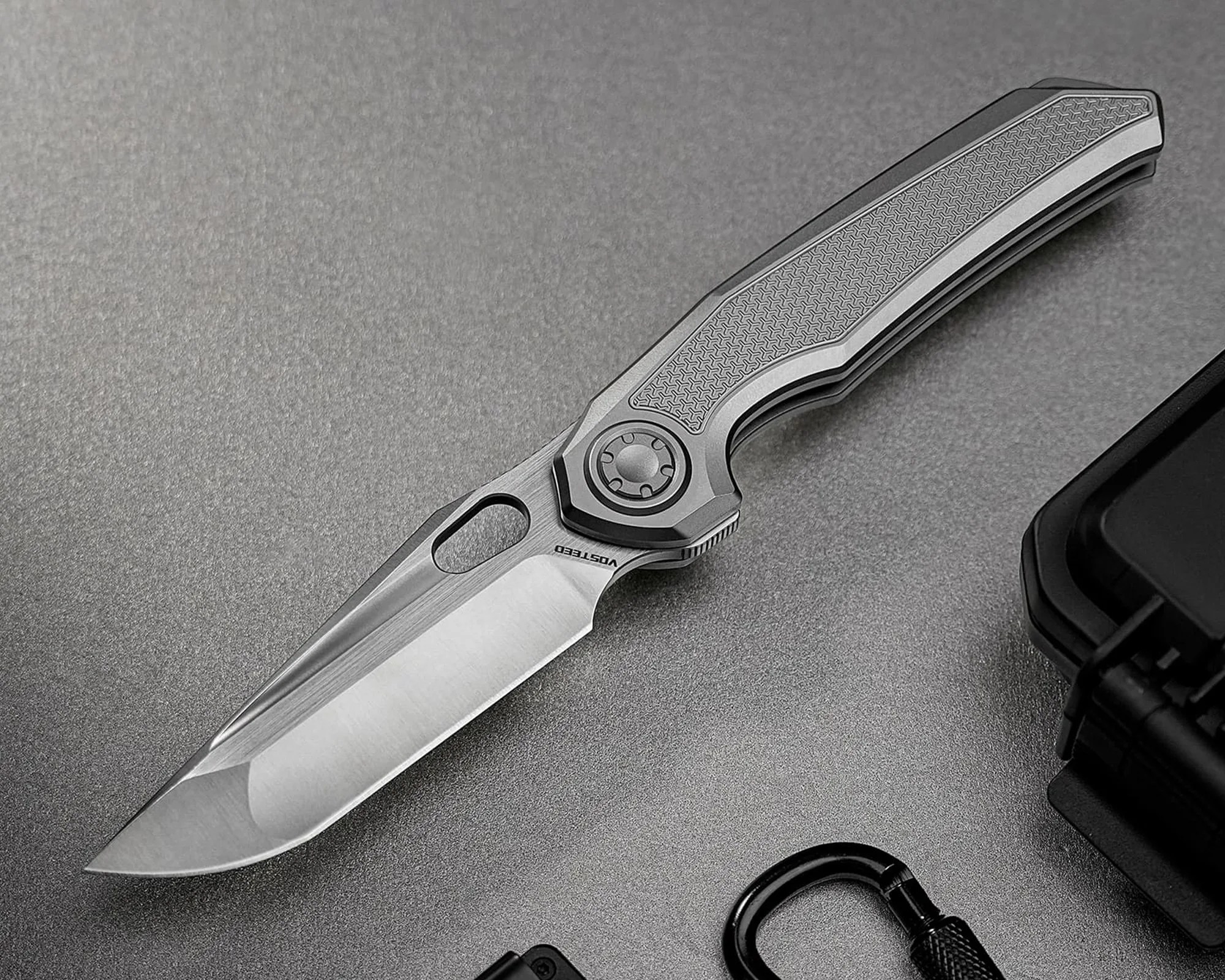 Folding knife with a textured gray handle and a partially serrated stainless steel blade on a gray surface.
